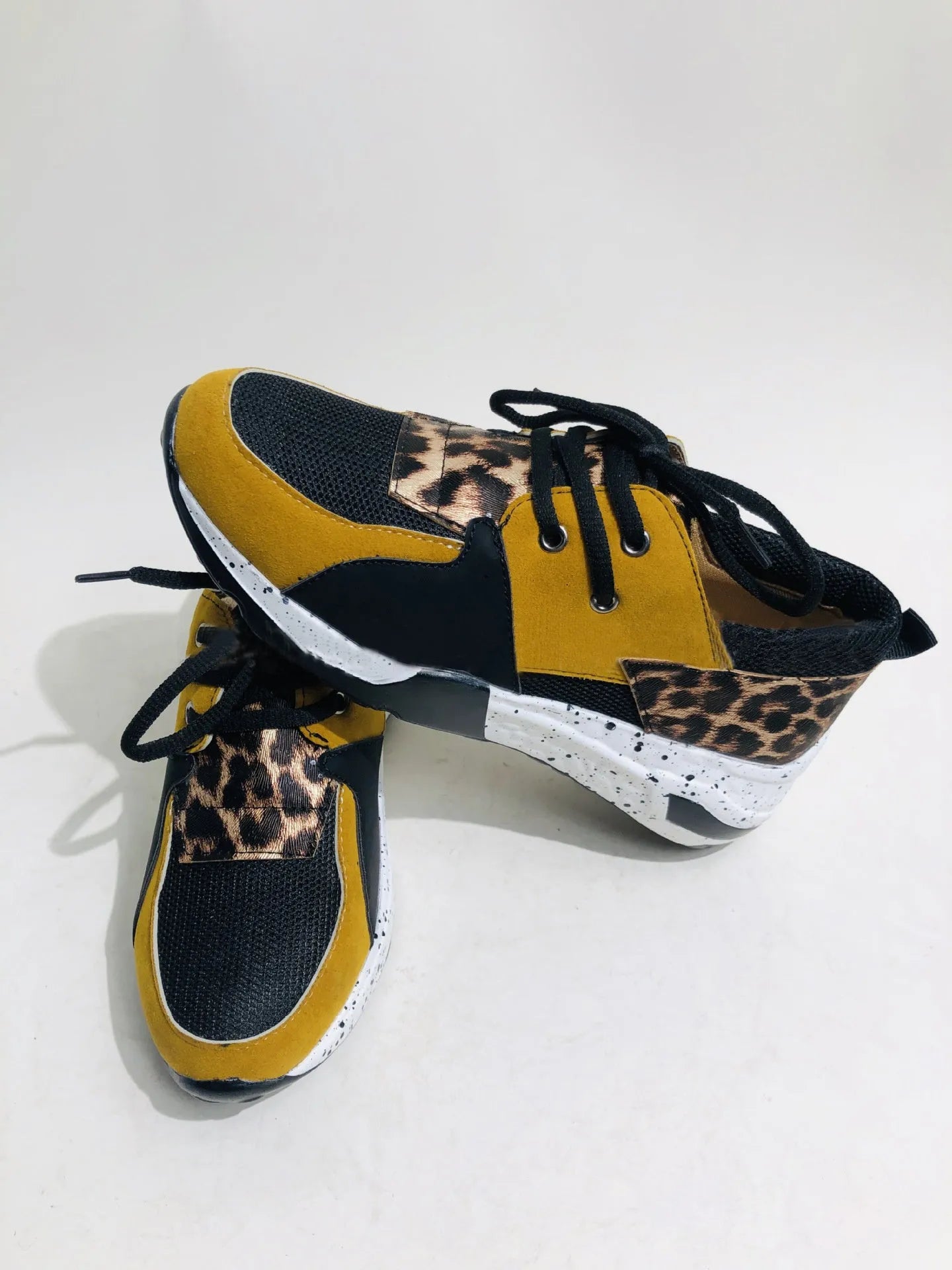 Women's black suede wedge sneakers with a round toe and low-cut design on a wooden floor.
