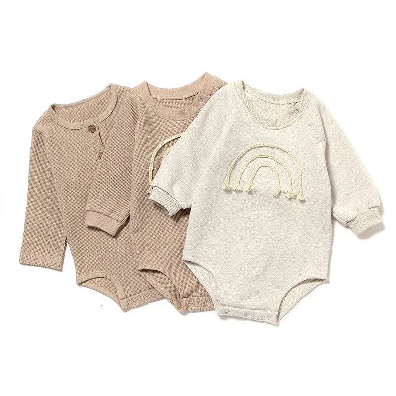 Baby wearing a beige waffle cotton long sleeve romper with rope ties, showing the triangle climbing style.