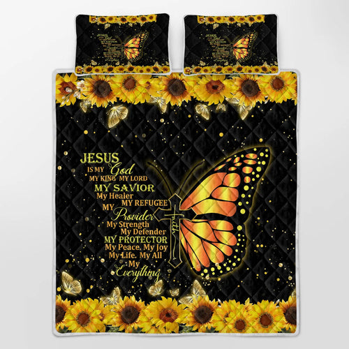 Three-piece black quilt set with butterfly and sunflower pattern, including quilt and two pillow shams, on a bed