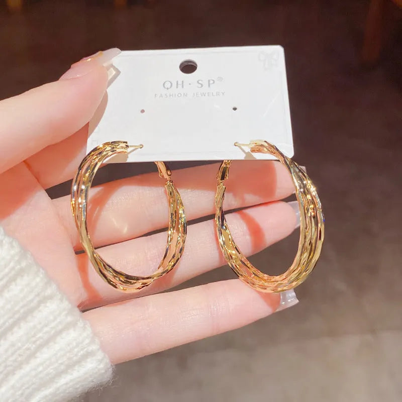 Gold and silver twisted metal earrings with copper body, round geometric shape, and silver needle for women.