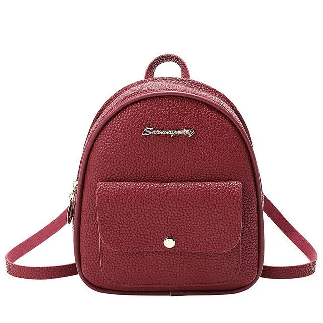 Small black PU women's backpack worn on shoulder, showing zip closure and compact size.