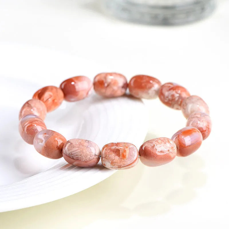 Natural cherry agate barrel bead bracelet with Ruyi charm on a wrist.