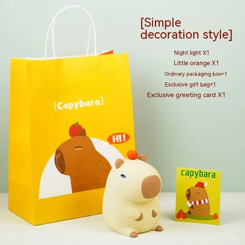 Small capybara-shaped night lamp in silicone and plastic, shown with USB cable.