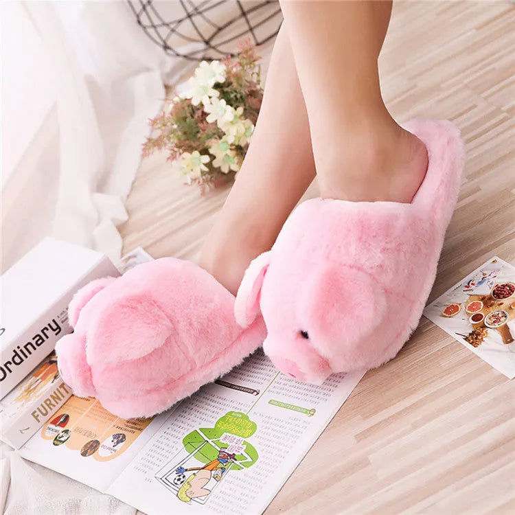 Pink pig-shaped plush house slippers with a short pile exterior, shown on a plain background.