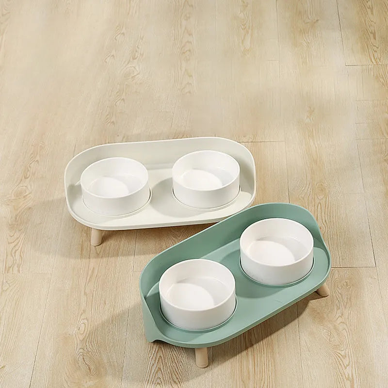 Green and white tilted pet feeder with two bowls for cats and dogs on a non-slip base.