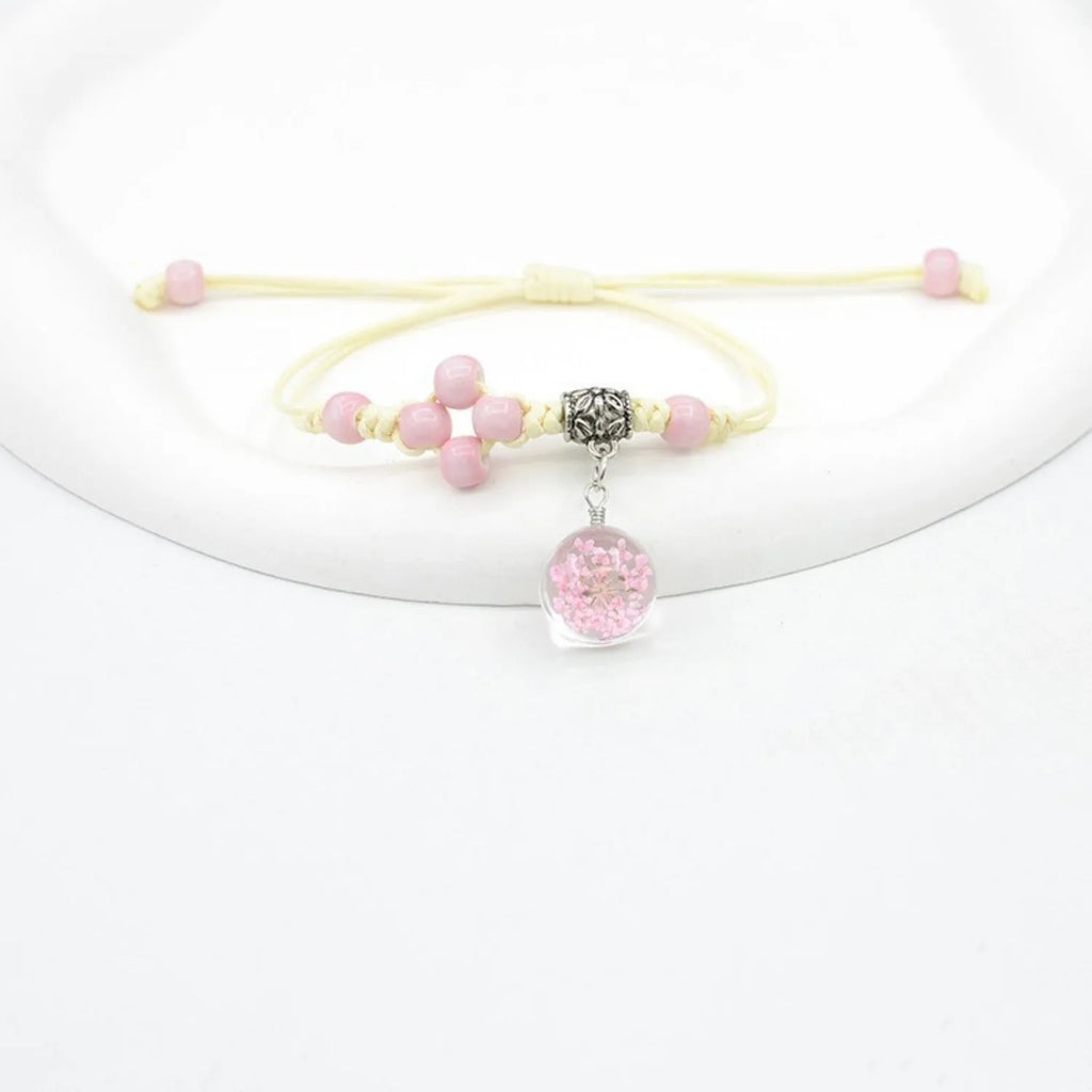 Close-up of a hand-woven glass bracelet with large 1.4cm beads containing real dried flowers and lace floral detailing.