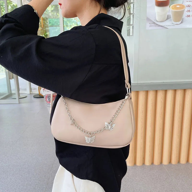 Retro-style light blue underarm shoulder bag with a silver butterfly chain strap, shown worn crossbody.