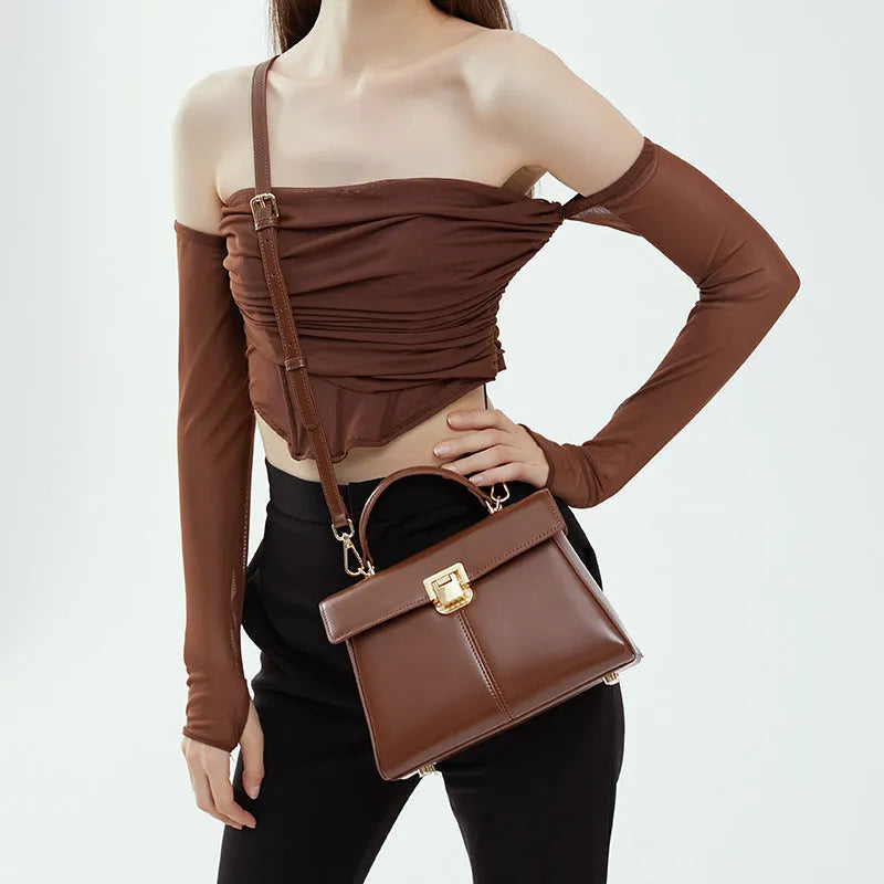 Black genuine leather women's shoulder bag with vachette clasp, showing horizontal square shape and adjustable strap.