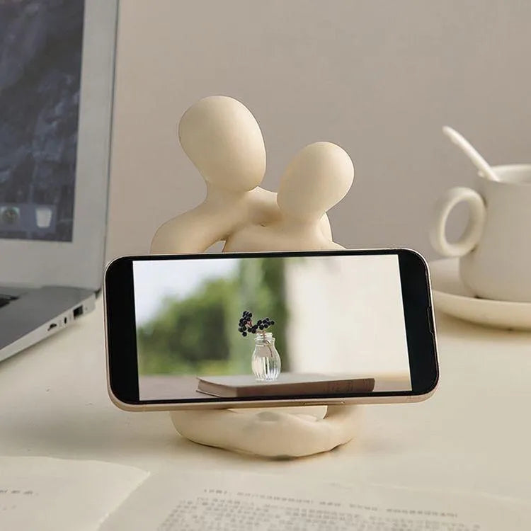 Modern resin statue of a loving couple in gold or milky white colour on a wooden surface.