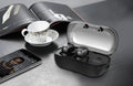 White TWS wireless in-ear sports headphones and compact rectangular charging case on a table.