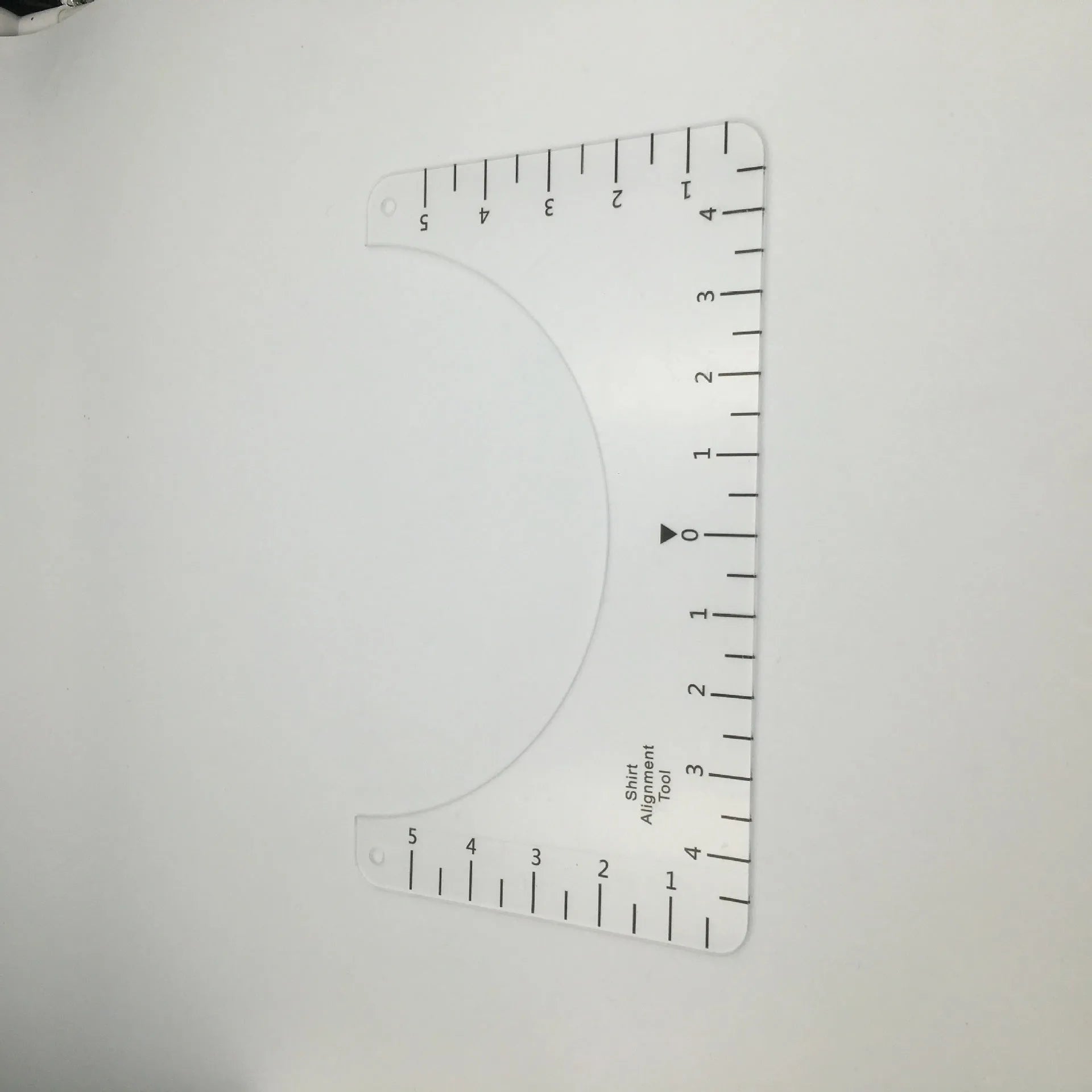 Transparent acrylic sewing ruler for T-shirt alignment and patch placement on fabric.