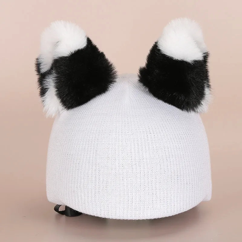 A plush fabric cartoon-themed decoration attached to the top of a blue ski helmet on a snowy slope.