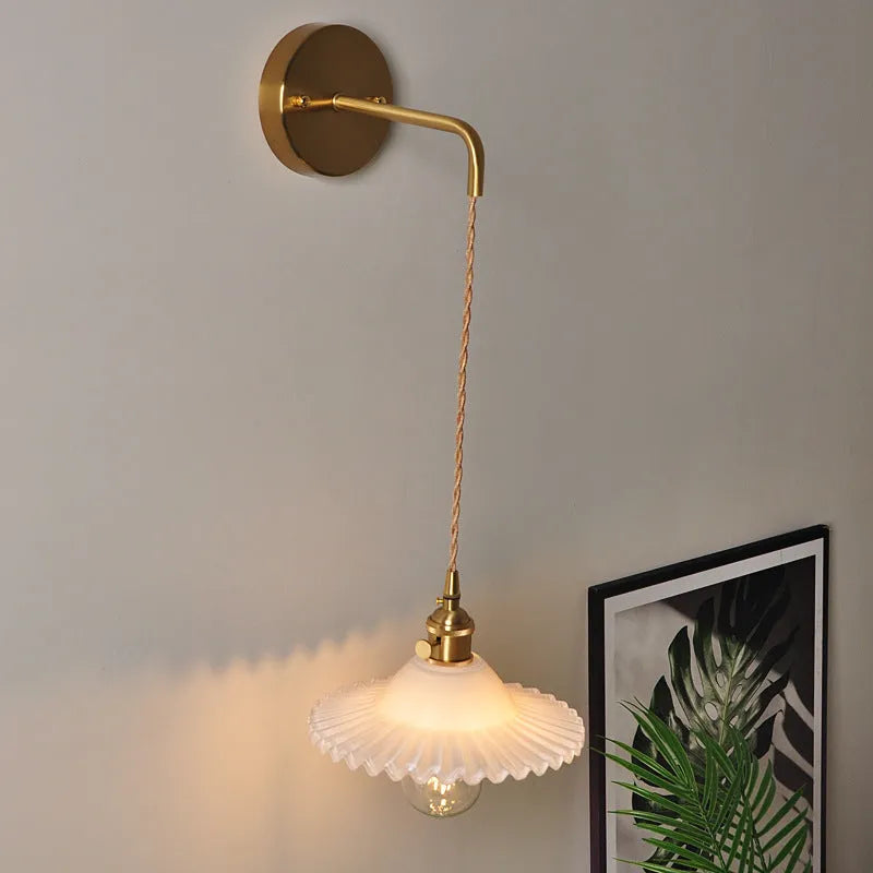 Retro brass lotus wall lamp with adjustable copper wire and white glass shade mounted on a wall.