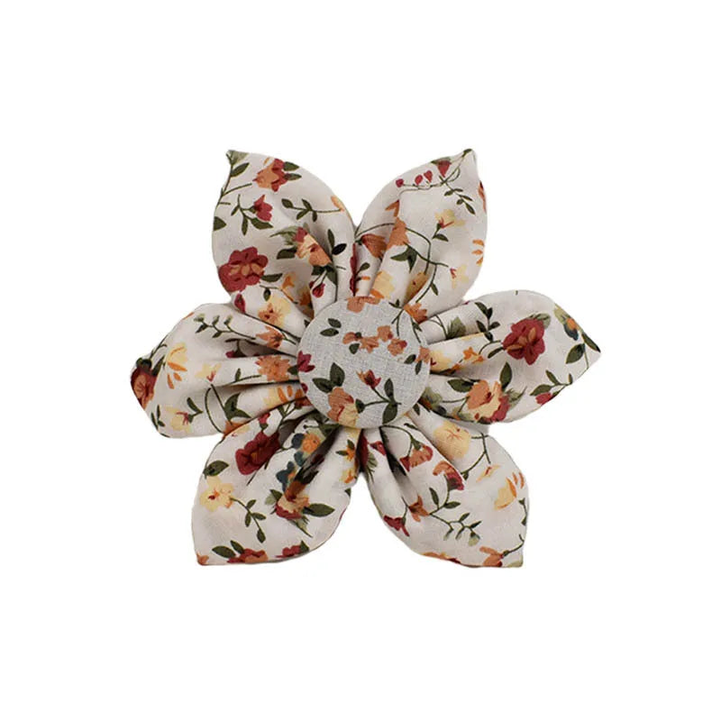 Small white flower pet dog collar set with matching vest, leash, bow, and accessories on a cloth background.