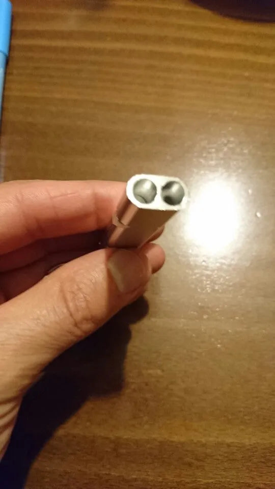 Close-up of a silver aluminium alloy double-hole outdoor survival whistle on a dark background.