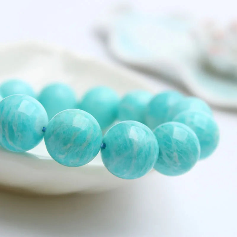 Natural blue-green amazonite gemstone bracelet with round polished beads on a white background.