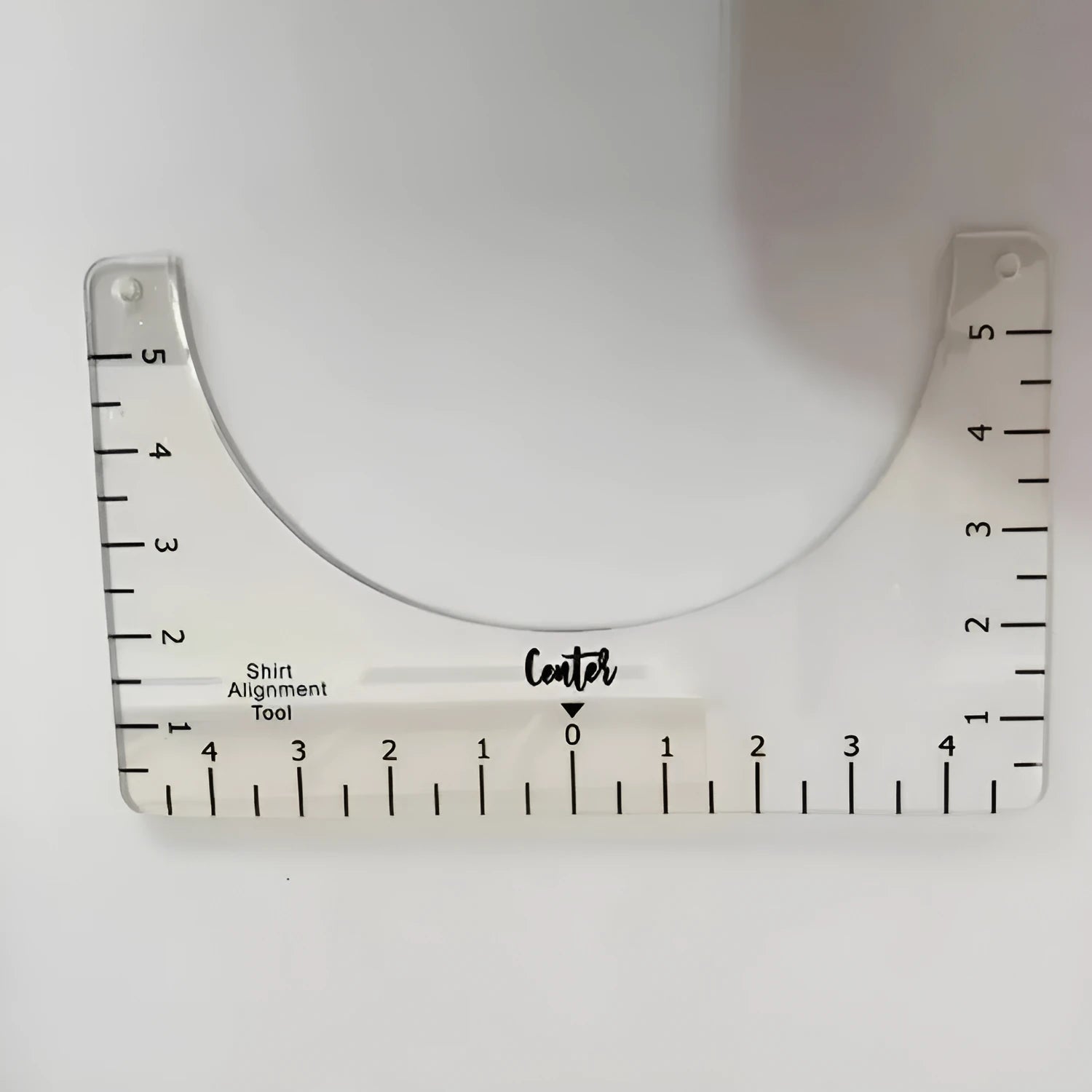 Transparent acrylic sewing ruler for T-shirt alignment and patch placement on fabric.