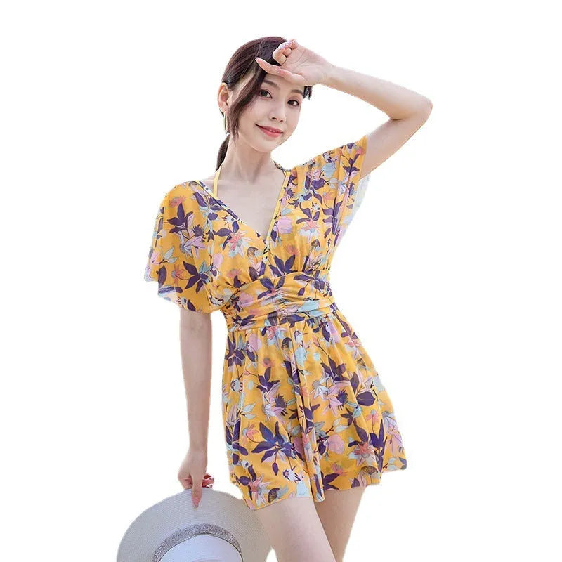 Yellow floral print women's one-piece swimsuit with skirted design on mannequin.