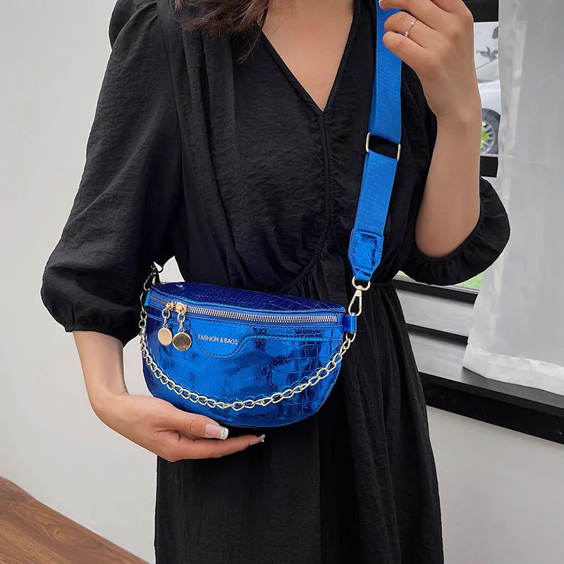 Shiny hard-shell PU chest bag with wide shoulder strap, chain detail, and internal pockets in silver colour