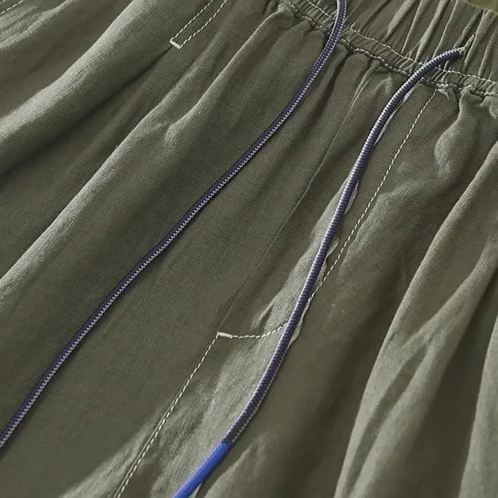 Men's loose fit linen shorts in green on a hanger, showing straight leg and drawstring waist.