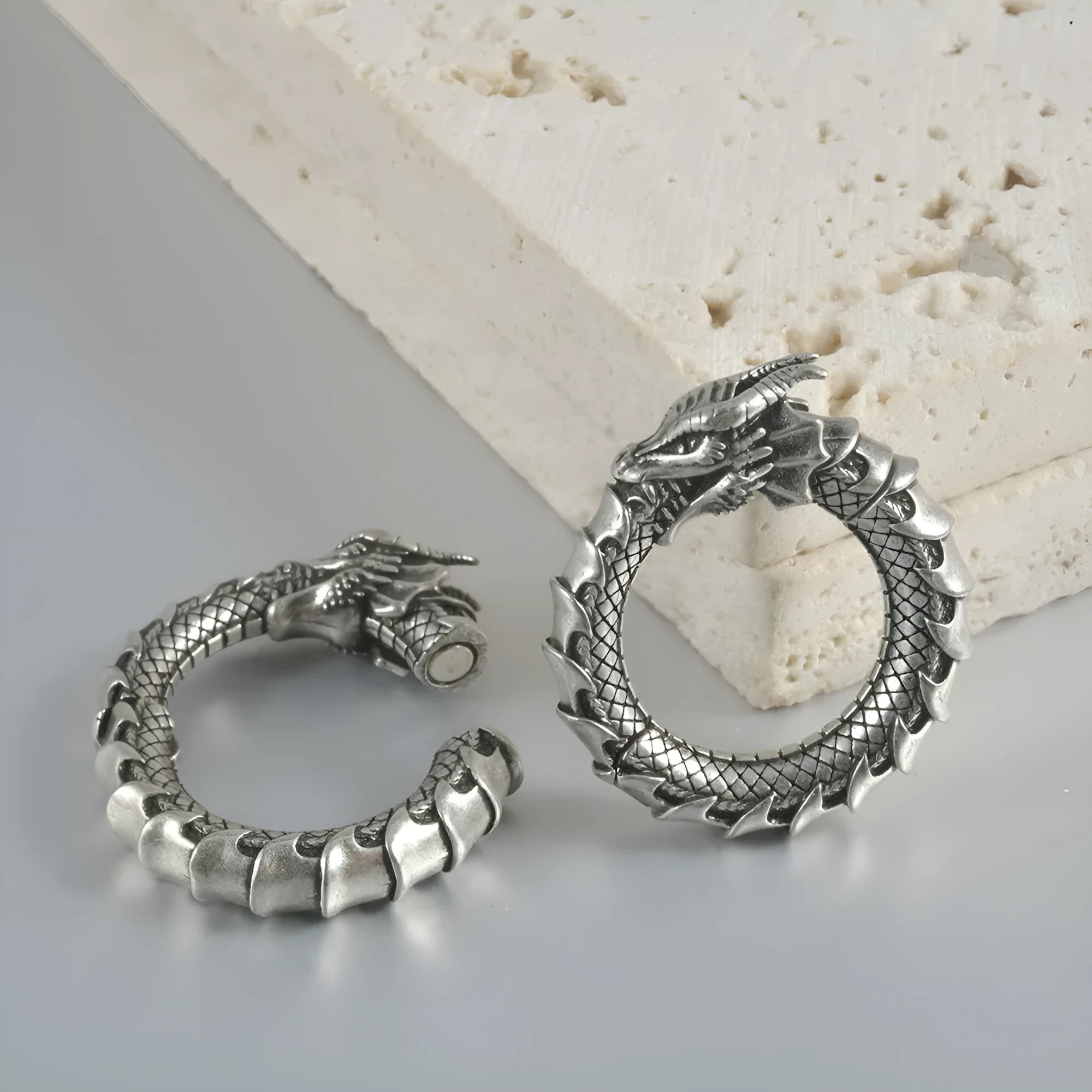 Pair of antique silver dragon-shaped hollow-out earrings with geometric design on a white background