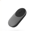 Black wireless Bluetooth mouse beside laptop showing compact design
