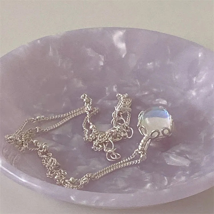 Women's silver geometric necklace with ornamental stone pendant on a curb chain.