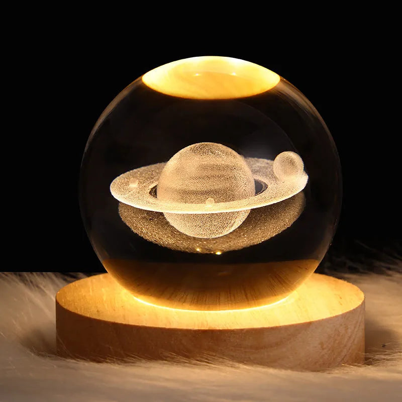 Clear crystal ball LED night light showing a 3D galaxy or planet design, lit from within on a table.