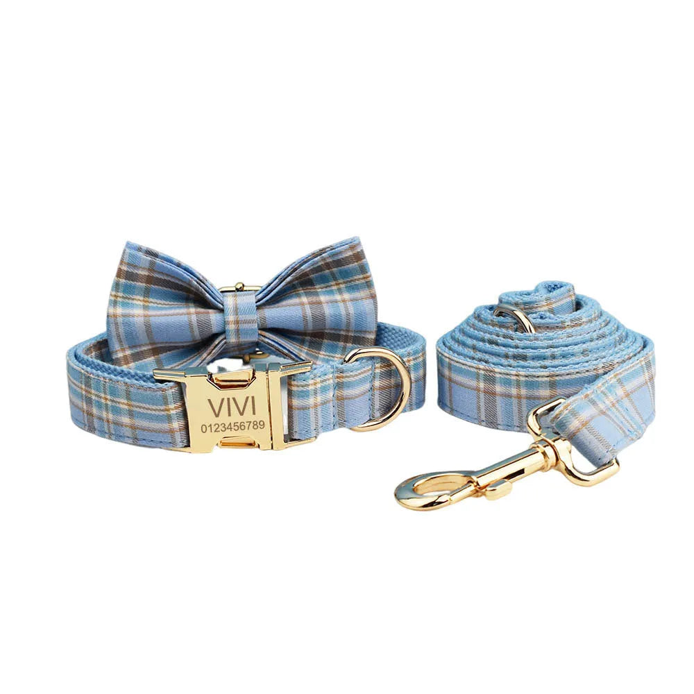 Sky blue grid pattern dog collar, leash, vest, and bow set laid out on a white background.