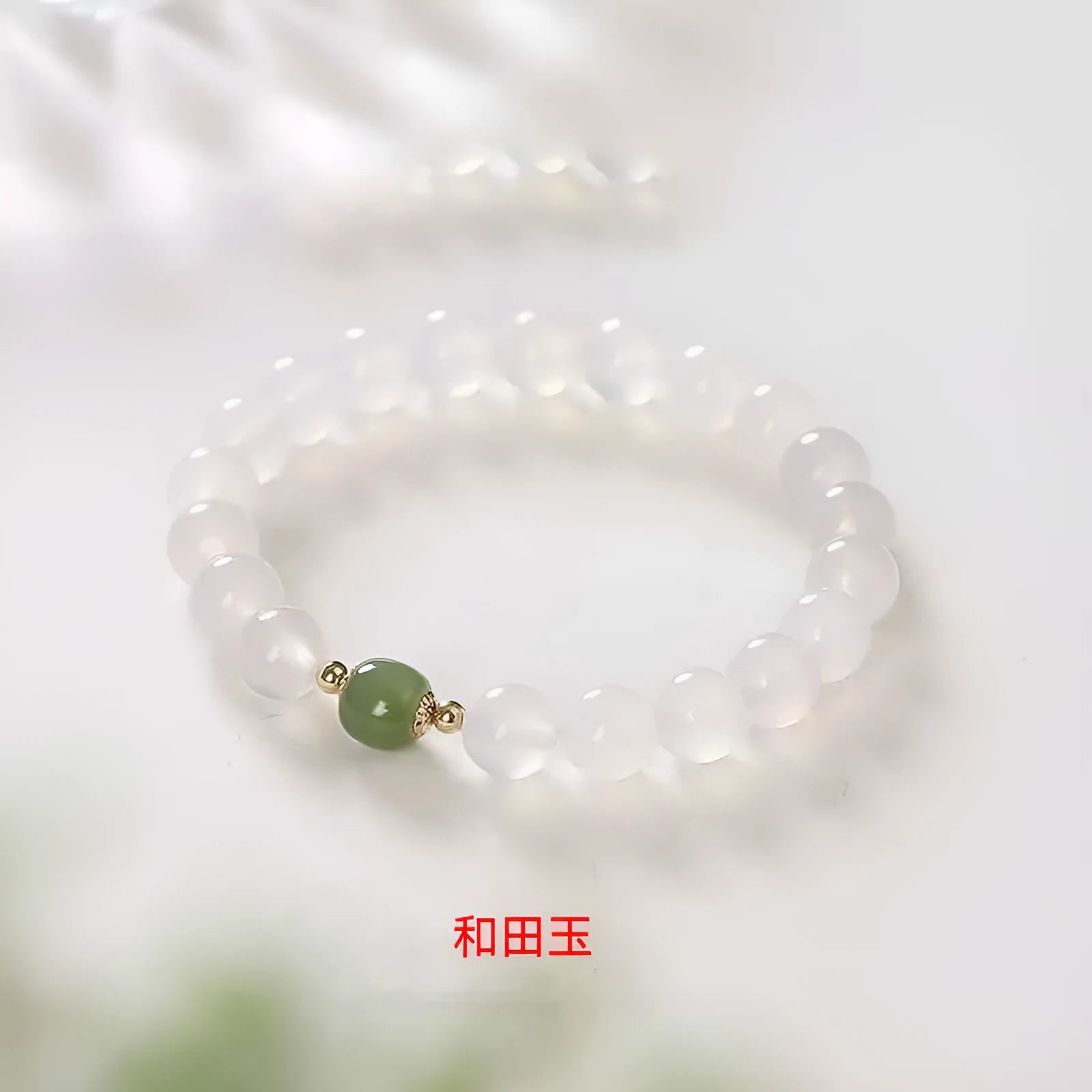 Handmade natural white agate and crystal bracelet with red cinnabar inlays on a wrist.