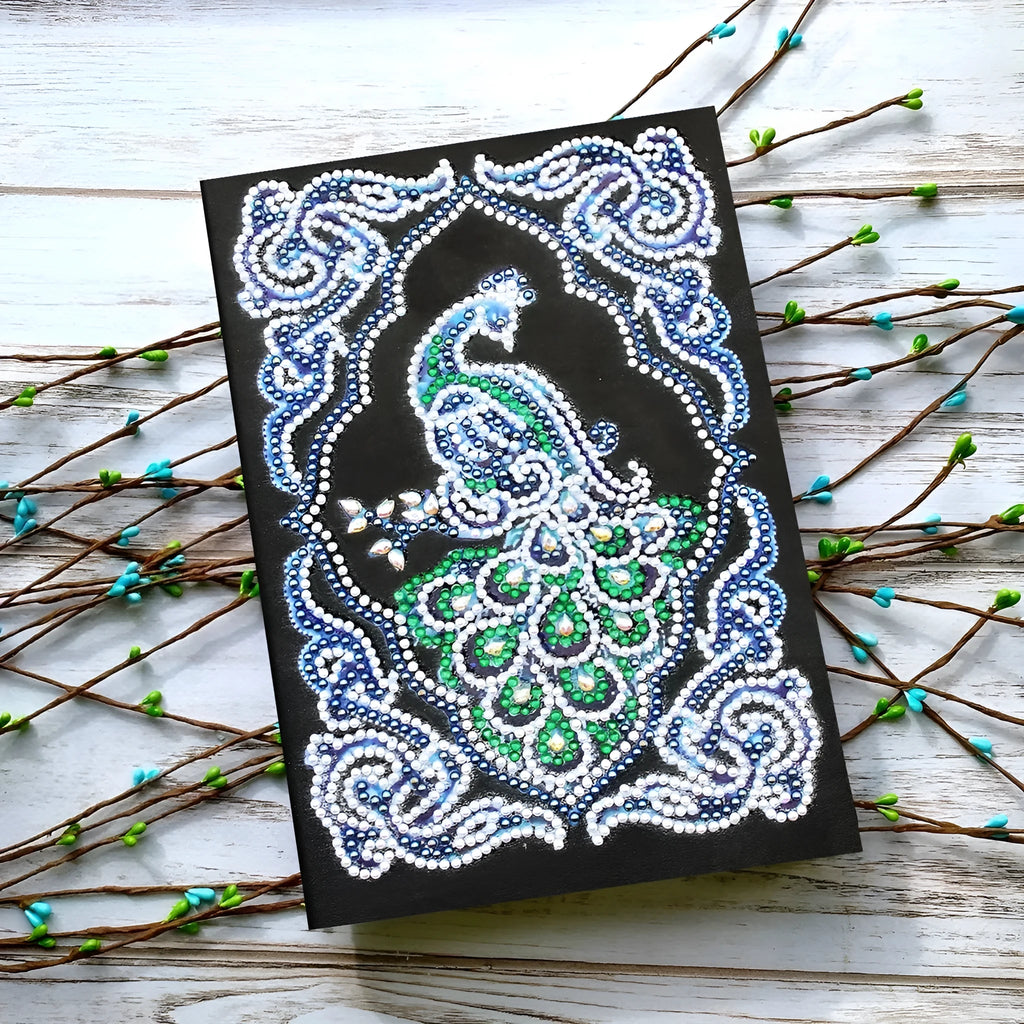 Black A5 diamond painting notebook open, showing journal pages alongside shaped and bright sparkling drills.