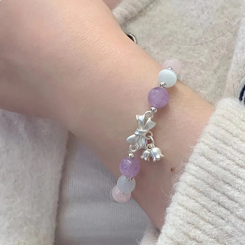 Lavender amethyst opal bracelet with a silver-toned bowknot design on a wrist.