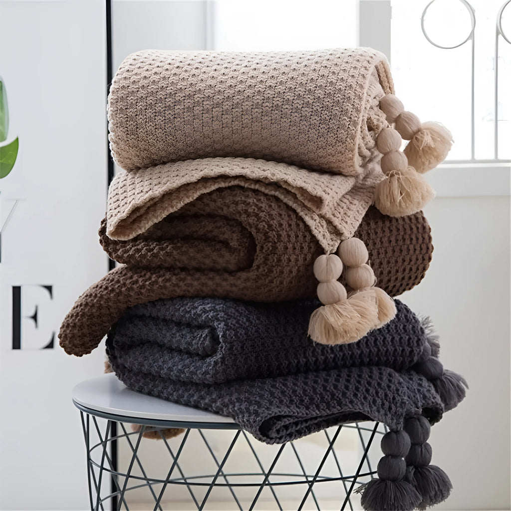 Nordic-style knit blanket with fringe trim in a neutral colour on a sofa