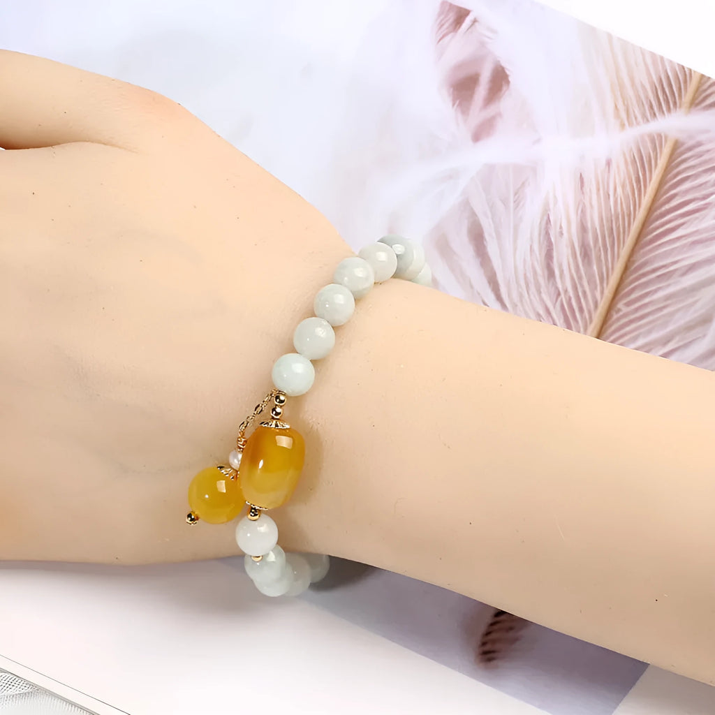 Women's ethnic bracelet with hanging red agate tassel on a gold chain.