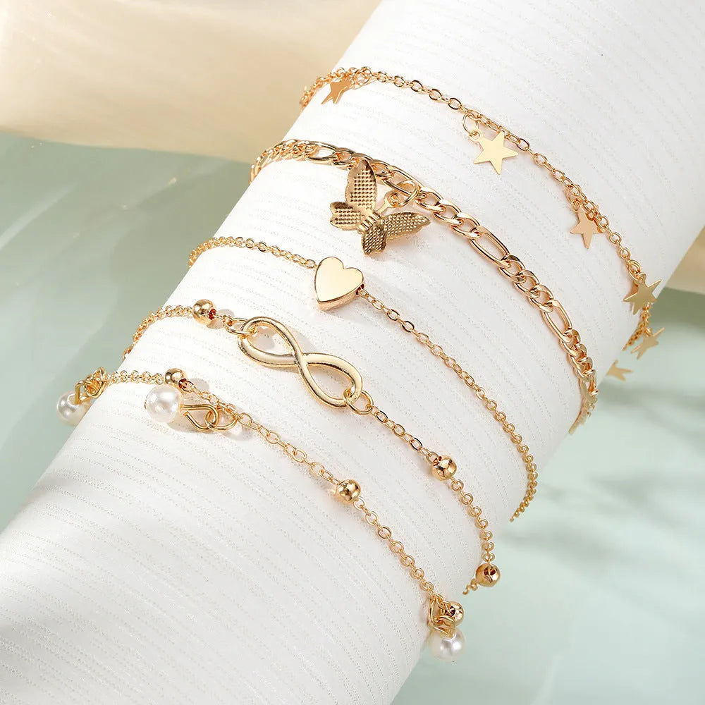 Set of four women's alloy anklets with butterfly and pearl heart designs arranged together