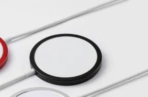 Silver aluminium MagSafe-compatible magnetic wireless charger for iPhone on a wooden desk.