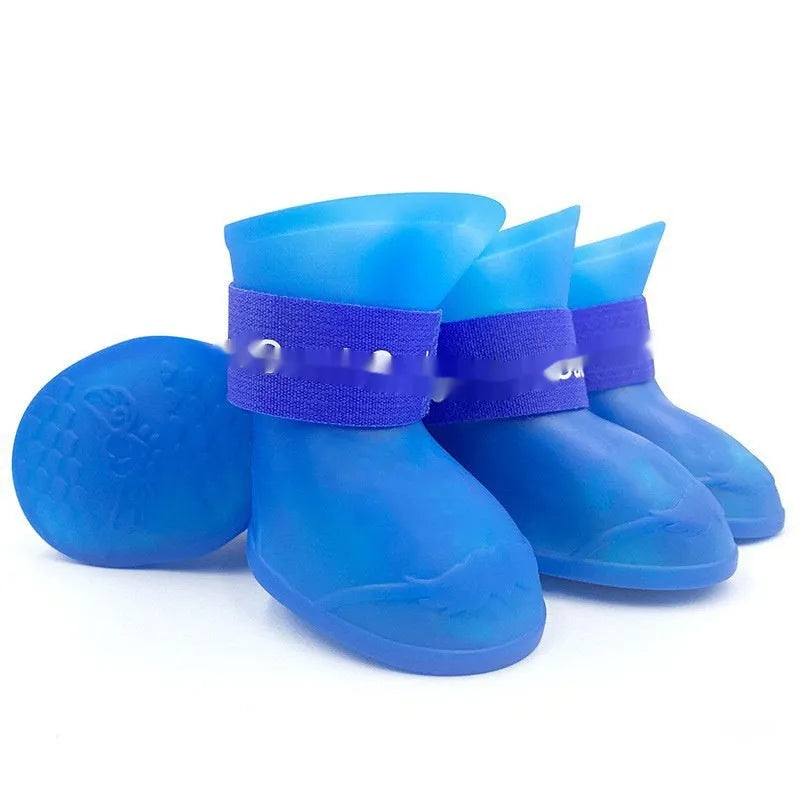 Set of four colourful rubber dog rain shoes with anti-slip soles on a wet surface.
