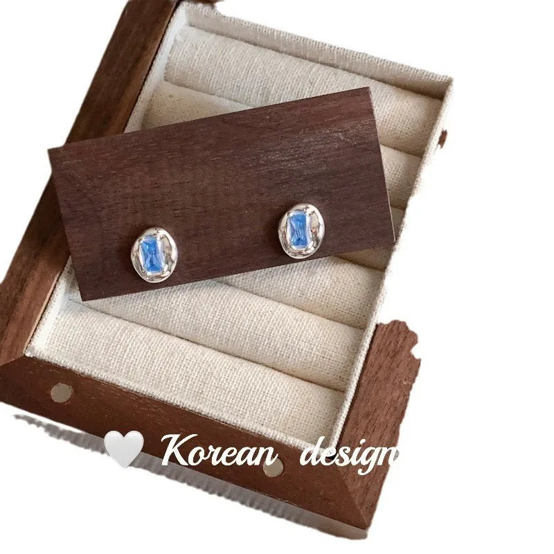 Silver geometric earrings with oval blue diamond wrapped in heart motif