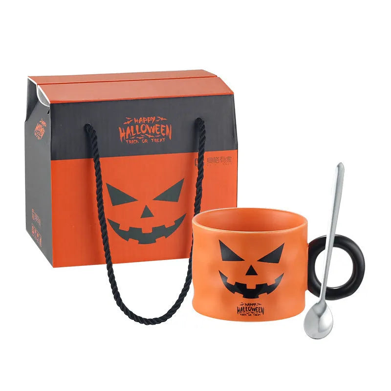 Orange ceramic Halloween pumpkin cup with handle beside dessert spoon in gift box
