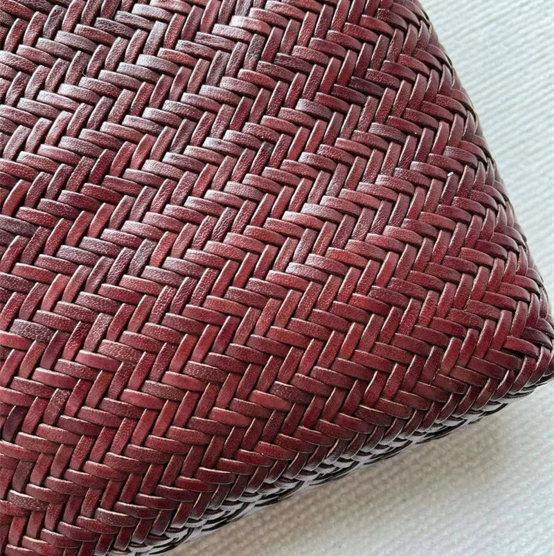 Brown handmade woven leather tote bag with a three-dimensional front pocket and shoulder strap.