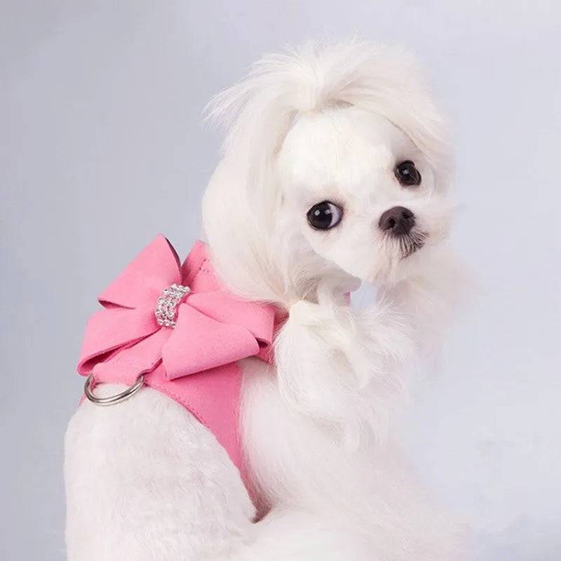 A pink dog harness with a white bow knot on an adjustable microfiber chest strap.