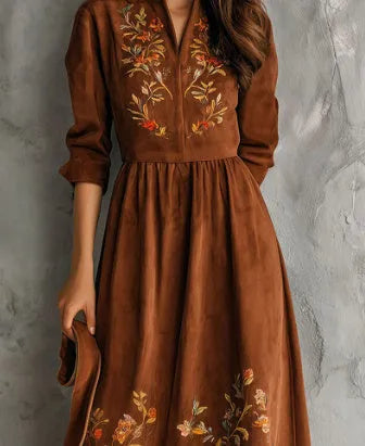 Brown suede-look midi dress with detailed floral embroidery on the bodice and hem, featuring three-quarter sleeves.