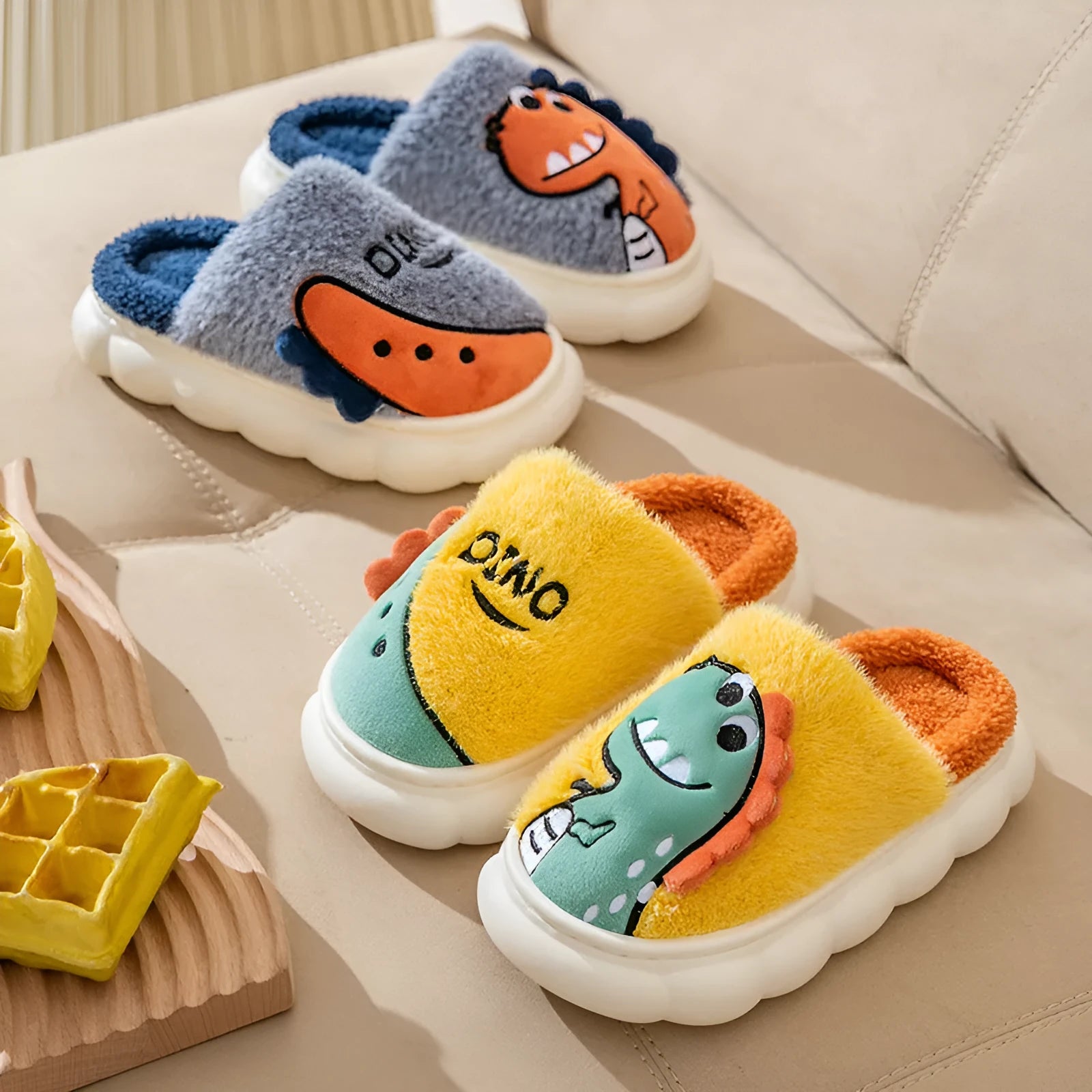 A pair of plush cotton indoor slippers with a thickened sole, shown in a dinosaur pattern colour.