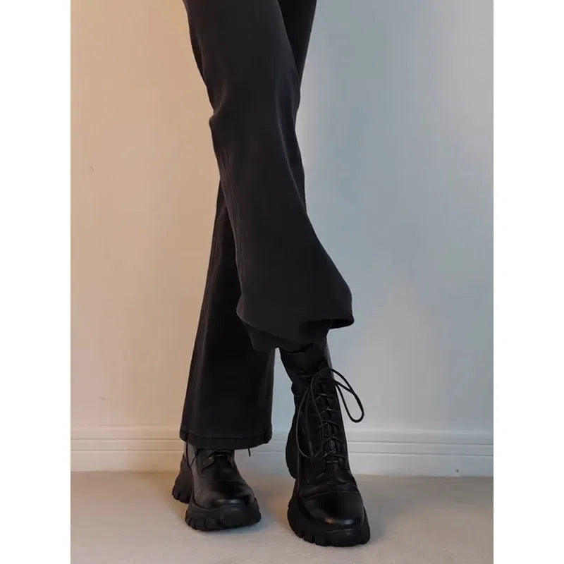 Black thick-soled motorcycle boots with back zipper, lace-up front, round toe, and rubber sole on a neutral background