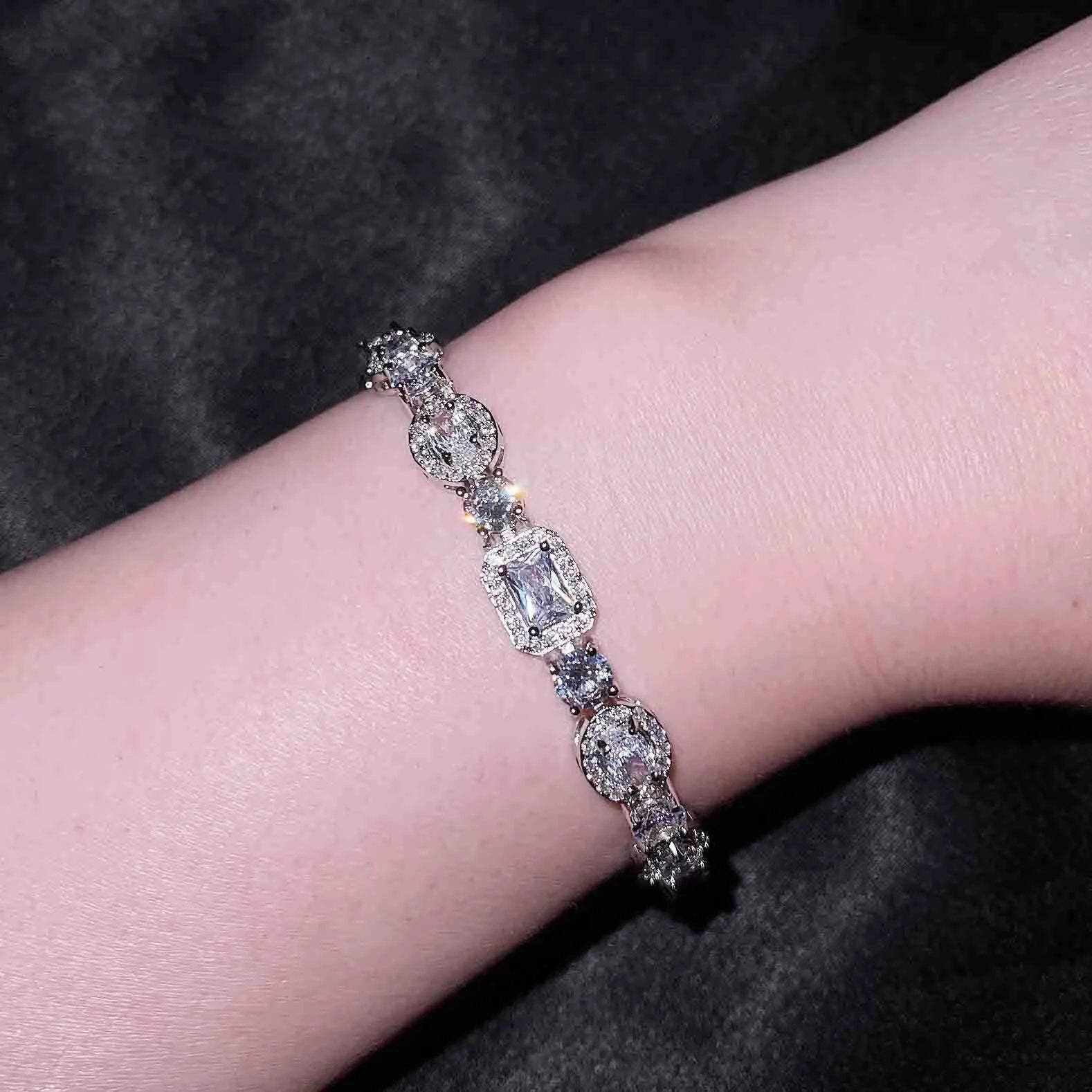 Close-up of a women's geometric silver bracelet with inlaid zircon stones on a wrist, showing adjustable chain.