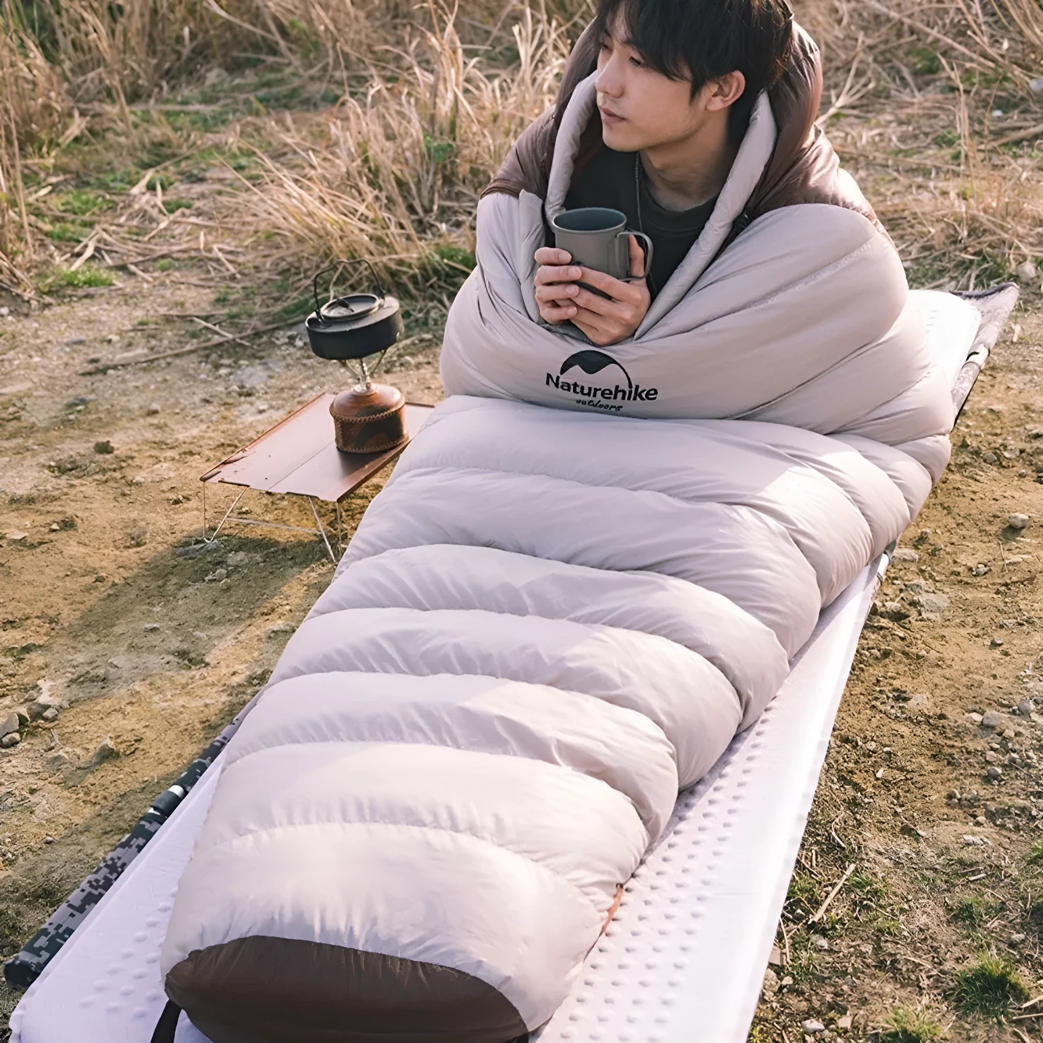 Blue and grey mummy-style down sleeping bag packed in its storage bag for camping.