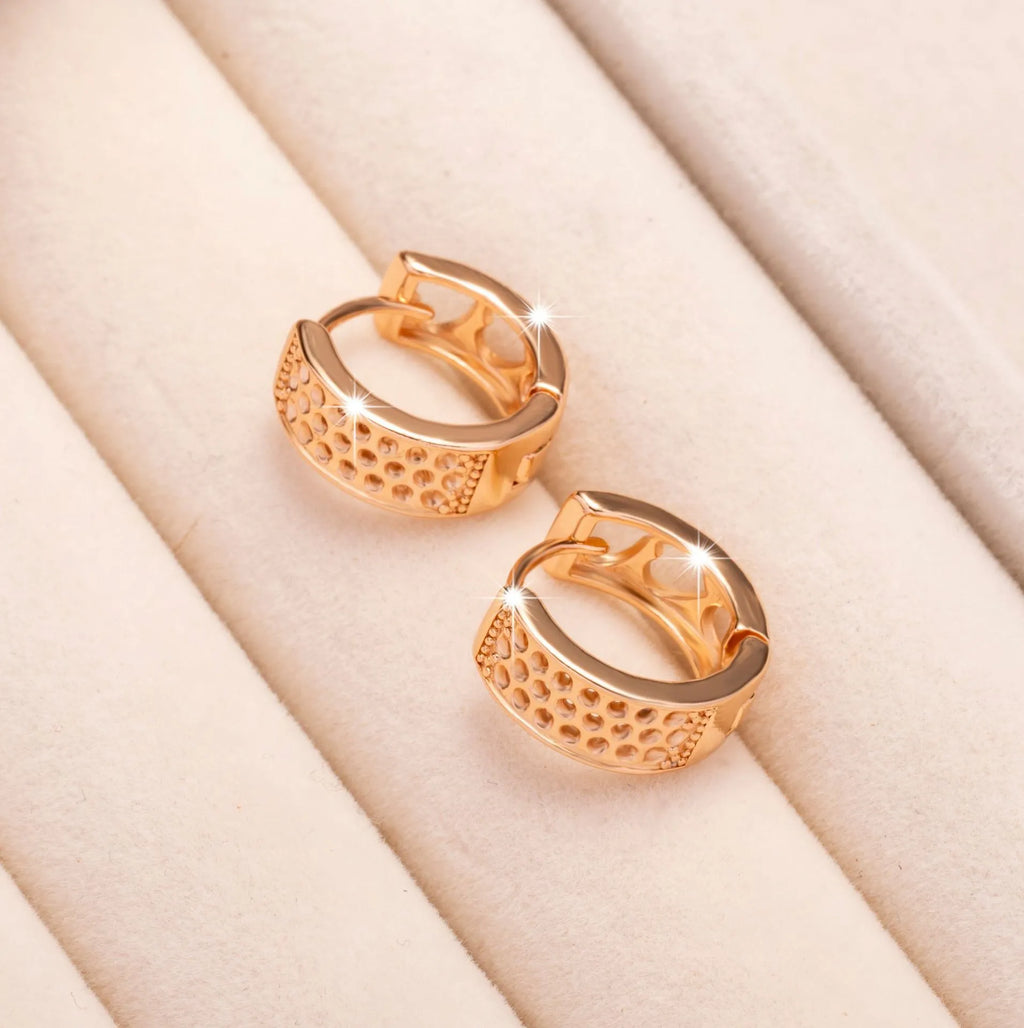 Close-up of a pair of rose gold circular hoop earrings with three small hollow heart shapes cut out of each band.