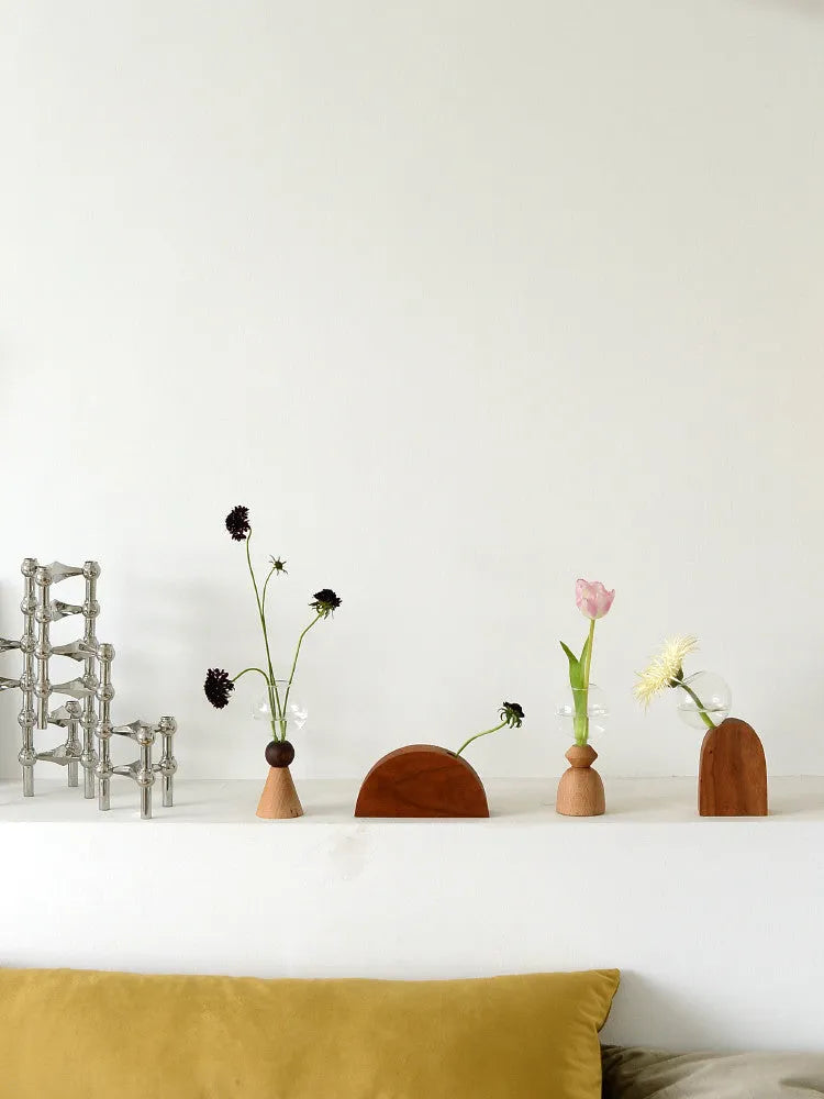 Small clear geometric bubble glass vase on a wooden base, shown with a single flower stem.