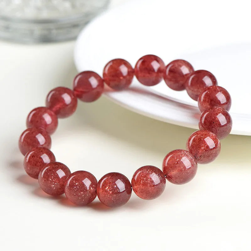 Cherry red strawberry quartz crystal bracelet with geometric beads on a wrist.