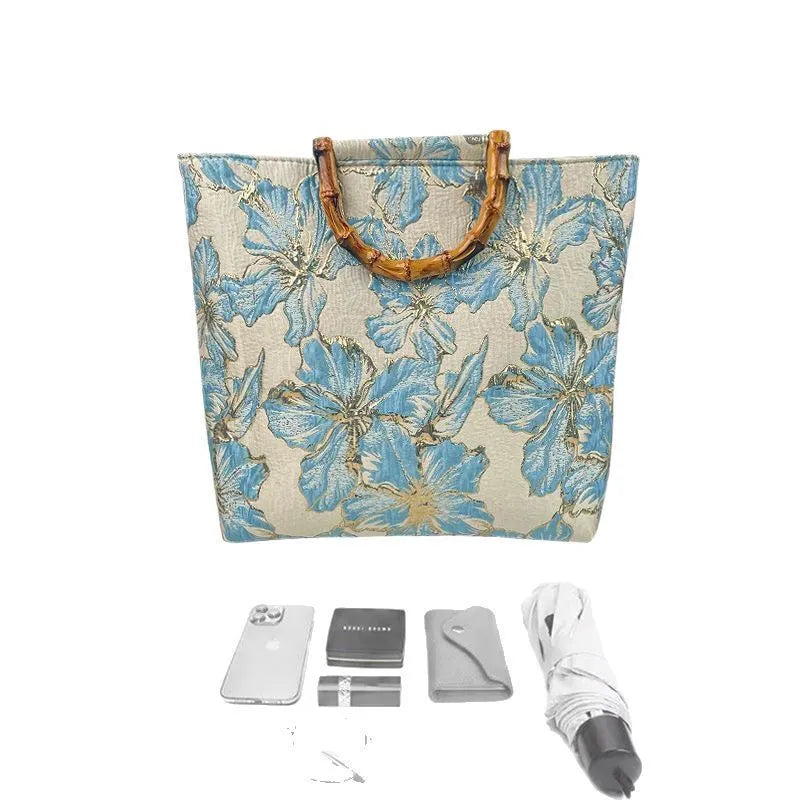 Light blue canvas bag with gold bronzing flower pattern, horizontal square shape, and dual shoulder straps.